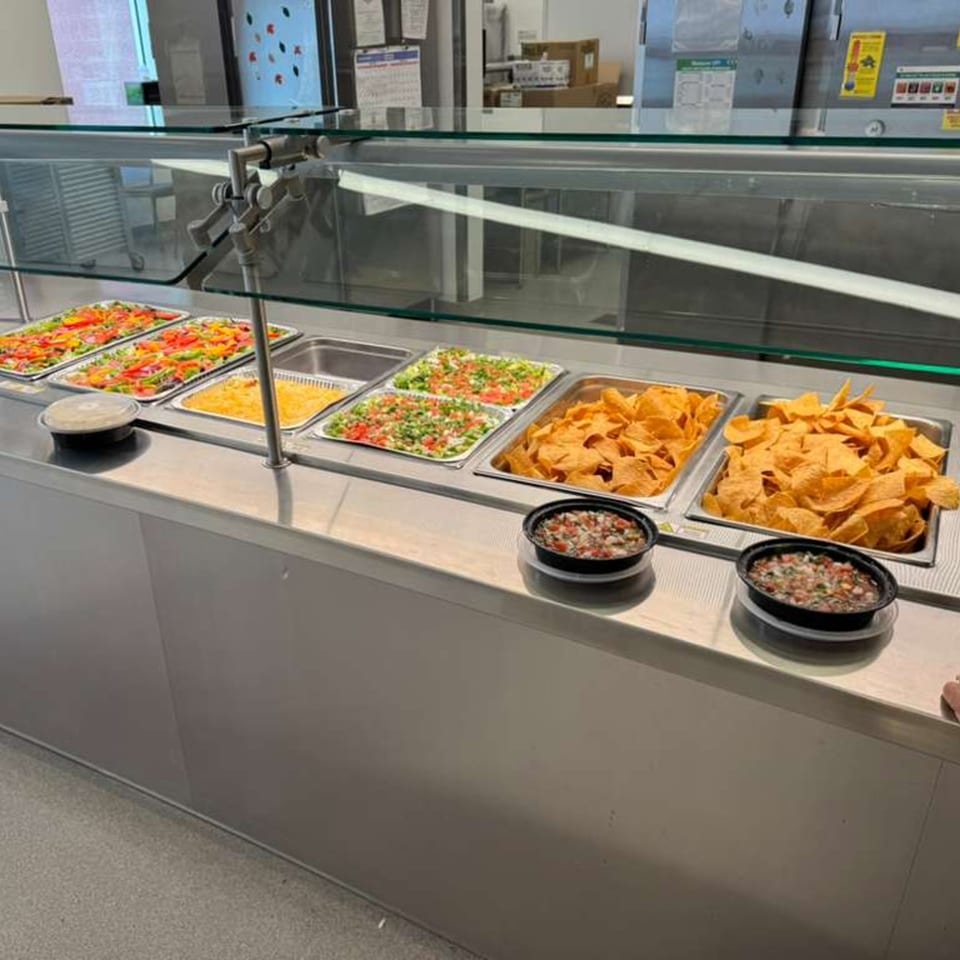 A buffet line at José's Torta Mexicana with various Mexican toppings, chips, and salsas.