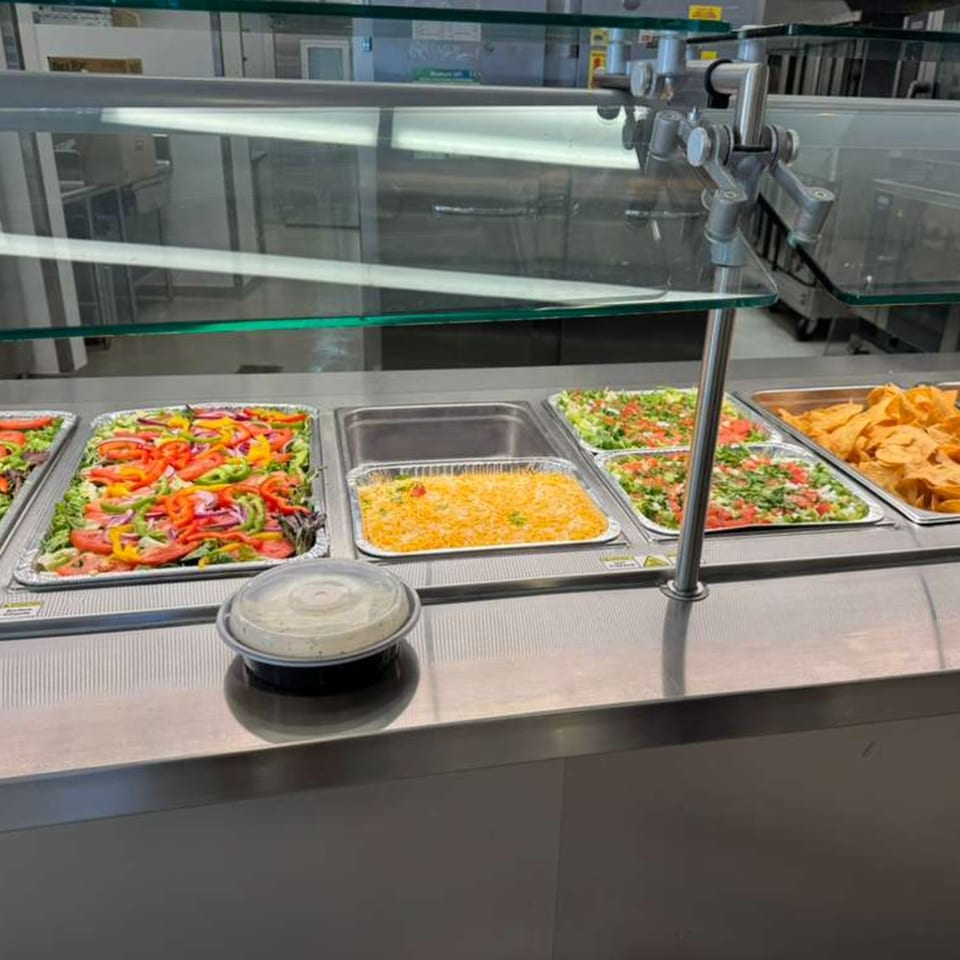 Buffet line with trays of fresh salads, cheese, and tortilla chips at José's Torta Mexicana.